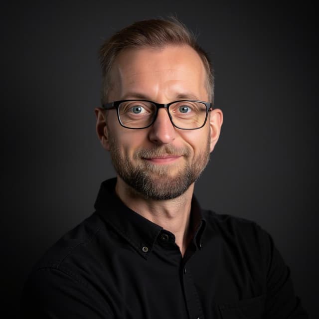 Headshot of Nico Puhlmann, wearing a a black business button up shirt.